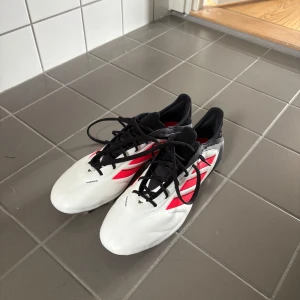 Adidas Copa vita och svarta fotbollsskor - Snygga Adidas Copa fotbollsskor i vitt med svarta och röda detaljer. Fick skorna av mitt fotbollslag men kan tyvärr ej ha adidas. Helt nya, aldrig använda. Har skobox. 