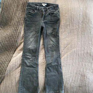 Grå bootcut jeans Gina Tricot 140 - Snygga grå jeans från Gina Tricot i storlek 140. Modellen har bootcut-ben, klassiska fem fickor och dragkedja med knapp. Knappen har dock rostat lite men syns inte. Jeansen är i mjukt denimtyg och har en cool, lite tvättad look. Perfekta för dig som gillar en avslappnad men trendig stil.🤩🌸