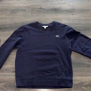 Mörkblå sweatshirt från Lacoste - Klassisk mörkblå sweatshirt från Lacoste med rund halsringning. Använd 2 gånger!