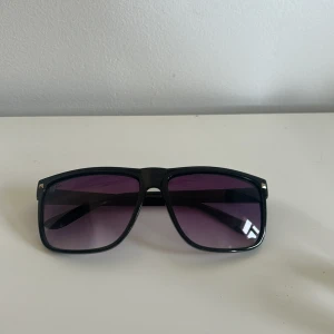 Svarta solglasögon från Ray-Ban - Snygga svarta solglasögon från Ray-Ban med rektangulära bågar och mörka, lila-tonade glas. Helt nya solglasögon. special Ray-Ban model.