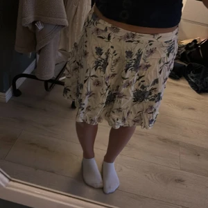 Blommig kortkjol från BikBok XS - Supersöt kortkjol från BikBok i vitt med blommigt mönster i lila och blå toner.  Resår i midjan för extra komfort och snyggt fall. Storlek Xs