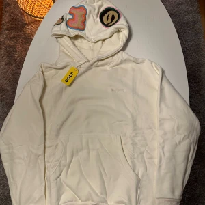 Golf WANG Hoodie Creme White - Sjukt snygg Golf Wang Hoodie i creme White med loggan sydd i mattliknande material på luvan. Tyvärr har jag tagit bort etiketten nu. Size S men väldigt oversized.