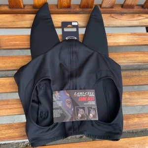 Svart huva för häst från Lami-Cell - Snygg svart huva från Lami-Cell med långa öron och kardborreband för enkel fastsättning. Tillverkad i mjukt syntetmaterial som sitter bekvämt på hästens huvud. Perfekt för ridning och tävling när du vill skydda hästens öron mot störande ljud.