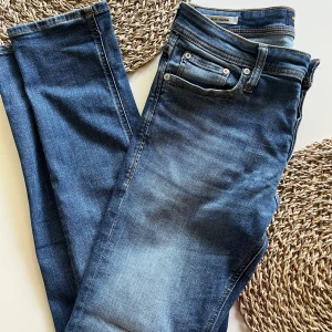 Blå slim jeans Jack & Jones Glenn - Snygga blå jeans från Jack & Jones, modell Slim/Glenn. Jeansen har en slim passform med klassisk femficksdesign och lätt slitning framtill.