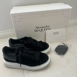 Svarta suede sneakers Alexander McQueen - Stilrena svarta suede sneakers från Alexander McQueen med tjock vit plattformssula och svarta skosnören. Ovandel i mocka och detaljer i skinn, klassisk rund tå och logga på hälen. Kommer med originalkartong, äktehetsbevis  och extra skosnören. Använd men i mycket bra skick!💗