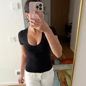 H&M v-ringad topp - En svart, tight och basic v-ringad topp med korta ärmar från H&M! Snygg passform som framhäver figuren och passar perfekt till jeans eller kjol. Enkel och stilren design💞