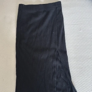 Svart ribbad långkjol Stradivarius - Svart långkjol från Stradivarius i ribbat material. Kjolen har en snygg slits på sidan och är figurnära i modellen.