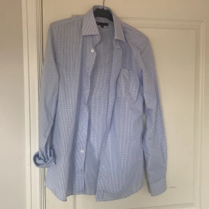 Blårutig skjorta från Dressmann S - Snygg blårutig skjorta från Dressmann i storlek S. Skjortan har klassisk krage, lång ärm och knäppning framtill. Tillverkad i mjuk bomull och passar perfekt till jeans eller chinos. Enkelt rutmönster i ljusblått och vitt ger en fräsch look.