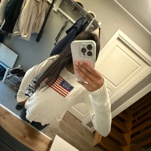 Vit stickad tröja Ralph Lauren S - Vit stickad tröja från Ralph Lauren med amerikansk flagga broderad på bröstet. Tröjan har rund halsringning, långa ärmar och ribbade muddar. Tillverkad i 100% bomull, perfekt för dig som gillar klassisk och clean stil.