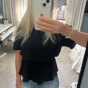 Svart blus med en resorbkant  - Svart blus med korta ärmar och som har resorb vid magen. 