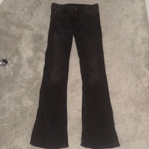 Svarta bootcut jeans från Cheap Monday - Svarta jeans från Cheap Monday med bootcut-passform och klassisk femficksdesign. Jeansen har en snygg svart tvätt och en stor vit patch med Cheap Monday-logga bak i midjan. Tillverkade i mjukt bomullsmaterial med lite stretch för extra komfort. Lite små i strl jag bär vanligtvis w27 o dom är lite tajta på mig. Längd 32💕