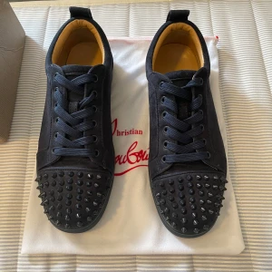 Mörkblåa  sneakers från Christian Louboutin - Snygga mörkblåa sneakers från Christian Louboutin i mocka med coola mörkblåa nitar på tån. Skorna har  tappat 8 spikar men de syns knappast vid användning .inget man tänker på dem. Skorna kan behöva en snabb tvätt som jag löser innan köp