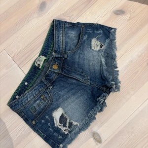 Blå jeansshorts med slitningar Terranova - Snygga blå jeansshorts från Terranova med slitna detaljer och fransig kant som är low waist! 