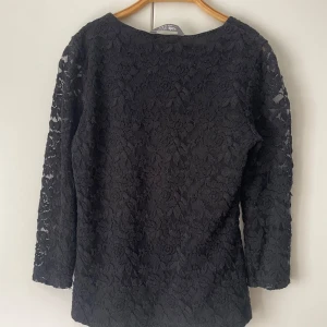 Svart spetsblus med trekvartsärm - Supersnygg svart blus från Lindex i spets med blommigt mönster. Blusen har trekvartsärmar och en rak passform som sitter bekvämt. Perfekt för dig som vill ha en stilren men ändå detaljrik topp. Funkar lika bra till jeans som till kjol.