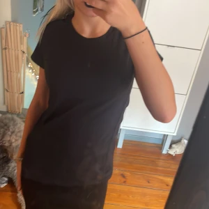 Svart sport-t-shirt från H&M 146/152 - Storlek 146/152Svart sportig t-shirt från H&M med rund hals och korta ärmar. Tillverkad i ett lätt och stretchigt syntetmaterial som andas, perfekt för träning. Enkel och clean design utan mönster, med en diskret rosa detalj på insidan av kragen.