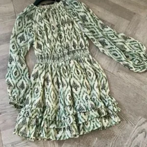 Grönmönstrad kortklänning med volang - Supersöt kortklänning med grönt och beige mönster, från ZARA men som inte säljs längre. Klänningen har volangkant nertill och är tillverkad i ett lätt, luftigt material. Klänningen är lite använd men fortfarande i jättebra skick.