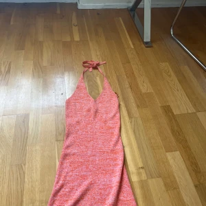Orange stickad halterneckklänning Bik Bok - Superfin orange och vit stickad kortklänning från Bik Bok med halterneck och knyt i nacken. Klänningen har v-ringning och är figurnära med en snygg, somrig vibe. Perfekt för dig som vill sticka ut med färg och mönster!