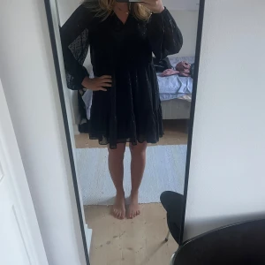 Svart glittrig klänning - Supersöt svart kortklänning från Gina Tricot med glittriga prickar och genomskinliga långärmar. Klänningen har en luftig passform, volangdetalj nertill och v-ringning. Om ni har några frågor är det bara att skriva💕💕