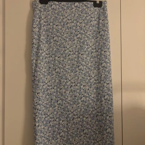 Blommig blå långkjol från lager 157 - Supersöt långkjol i ljusblått med små vita och svarta blommor från lager 157. Den har en fin slits där bak. Använd 1 gång, köparen står alltid för frakten💞
