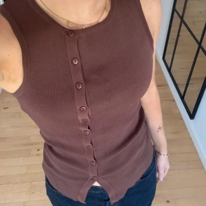 Brun ribbad linnetopp från Glassons - Säljer en brun ribbad linnetopp från Glassons med knappar hela vägen framtill. Toppen är ärmlös och har en tight passform som sitter snyggt mot kroppen. Lånade bilder! Ge gärna prisförslag!!