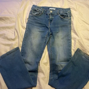 Blå jeans från Name It, storlek 146 - Säljer ett par klassiska blå jeans från Name It i storlek 146. Jeansen har normal passform, fem fickor och snygga slitningar framtill. Materialet är mjukt denim och midjan är elastisk för extra komfort. Perfekta till vardags med en hoodie eller t-shirt. Säljer pga för små!💞