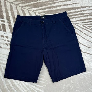 Mörkblå shorts  - Klassiska mörkblå shorts från 157 i mjuk bomull. De har normal passform, sidofickor, bakfickor med knapp och bälteshällor. Perfekta för sommardagar när du vill ha en clean och enkel stil. 