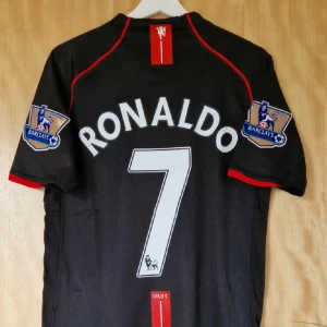 Manchester United  - Helt ny har tags kvar, Säljer en svart Manchester United fotbollströja med Ronaldo 7 på ryggen. Tröjan har röda detaljer, vita tryck och Premier League-märken på ärmarna. Framsidan har AIG som sponsor och klubbmärke. Tillverkad i ventilerande polyester, perfekt för match eller samling.