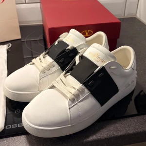 Valentino Garavani Open sneakers vit/svart - Snygga Valentino Garavani Open sneakers i vitt skinn. Säljes pga för små för mig. Otroligt sköna skor, har haft liknande i flera år och dessa tröttnar man aldrig på. Originalpåse, kartong och dustbag medföljer. Använda ett fåtal gånger. BVSA