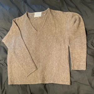 Beige v-ringad stickad tröja Samsa - Mysig beige stickad tröja från Samsa Collection i storlek S. Tröjan har v-ringning och långa ärmar, perfekt för lager-på-lager. Enkel och stilren design som funkar till många outfits.