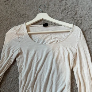 Vit långärmad topp från Gina Tricot - En basic vit långärmad topp från Gina Tricot med rund halsringning. Enkel och stilren modell i mjukt material, perfekt att matcha med jeans eller kjol. Tunt och luftigt material.