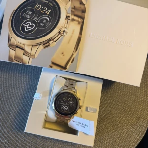 Smartwatch Michael Kors Access - Snygg smartwatch från Michael Kors Access med digital urtavla och länkarmband i metall. Perfekt för dig som vill ha både teknik och mode på handleden.