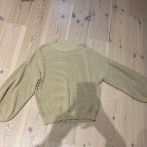 Beige stickad tröja med ballongärm - Snygg beige stickad tröja med ballongärmar och ribbad kant nertill. Tröjan har en högre halsringning och är perfekt för lager-på-lager-stil. Enkel att matcha med både jeans och kjol.