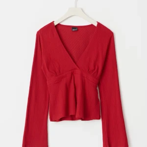Röd omlottopp med knyt från Gina Tricot❤️ - Snygg röd omlottopp från Gina Tricot med v-ringning och långa ärmar. Toppen har ett knytband i midjan som ger en fin siluett och lätt croppad passform. Perfekt att styla med jeans eller kjol för en trendig look!❤️🌟😆