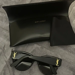 Saint Laurent solglasögon  - Säljer mina Saint Laurent solglasögon, modell SL M3 002 i svart. Bågbredd: 140 mm. Fick dem i present men de är tyvärr lite för stora för min ansiktsform. Är i mycket fint skick – inga repor eller skador. Stilrena och bekväma – perfekta för både vardag och fest. Nypris: 3959 kr.