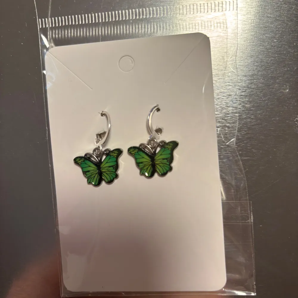 Snygga örhängen med gröna fjärilar som hänger från en silverfärgad krok. Perfekta för att lägga till en färgglad touch till din outfit. 🦋 (billigt material) . Asusteet.