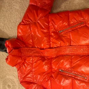 Röd pufferjacka från ASOS - Säljer en snygg röd pufferjacka från ASOS. Jackan har en glansig finish och praktiska dragkedjefickor framtill. Perfekt för att hålla värmen under kyliga dagar. Hör av dig vid intresse! 🔥