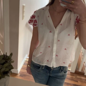 Blus med röda detaljer - En fin blus med röda detaljer, passa till finare tillfällen men även vardagen. Säljer då den inte kommit till användning för mig tyvärr. Köpte den i Spanien på ett köpcentrum men den butiken finns inte här 