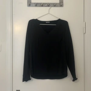 Svart långärmad tröja med v-ringning - Säljer en stilren svart tröja med v-ringning och långa ärmar. Perfekt för en elegant och enkel look. Passar bra till både jeans och kjol.