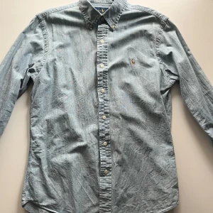 Ljusblå skjorta från Ralph Lauren - Säljer en stilren ljusblå skjorta från Ralph Lauren i slim fit M. Perfekt för en klassisk look.
