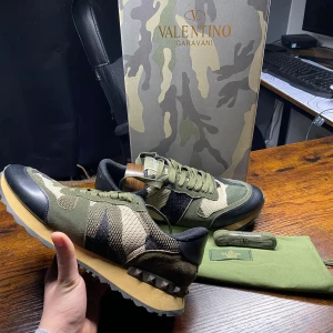 Valentino Rockrunner  - Exklusiva Valentino Garavani Rockrunner sneakers i ett snyggt camouflage-mönster! En perfekt kombination av lyx och streetwear, med premiumkvalitet och de ikoniska nitarna vid hälen. |  Färg: Camouflage (camouflage) 🪖 | Material: Mix av mocka, mesh och läder 🏆| Skick: Nästan nya🙌 | Storlek: 44 👌| Tillbehör: Originalbox, dustbag, Skosnören  📦✨ | 🚚 Leverans: Skickas snabbt via PostNord eller instabox | 💬 Skicka ett meddelande vid frågor!