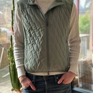 Colmar  - Snygg grön quiltad väst från Colmar med dragkedja och hög krage. Perfekt för lager-på-lager-stil. Västen har praktiska fickor med dragkedja och en stilren design. storlek S 
