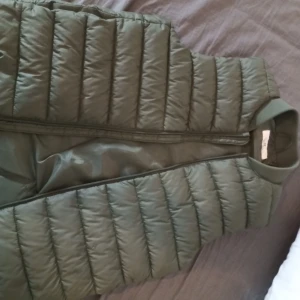 Grön hm väst - Säljer en snygg grön hm väst med dragkedja. Perfekt för lager-på-lager under kyliga dagar. Västen har en stilren design och är lätt att matcha med olika outfits. Kan även användas på sommaren. Använd två gånger.
