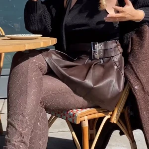 Brun kjol från NA-KD - Snygg brun kjol från NA-KD i skinnimitation med dubbla bältesdetaljer i midjan. Kjolen har en kort och utsvängd design som ger en cool look. Perfekt för att ge din outfit en edgy touch! Blivit skrynklig pga legat i garderoben men fixas lätt med en liten steam!