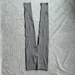 Grå randiga tights från Zara - Snygga grå randiga byxor från Zara. De har en tight passform och är tillverkade i ett ribbat material som ger en skön stretch. Perfekta för en stilren look.