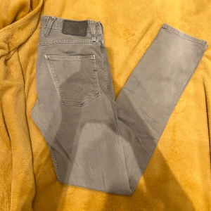 Replay anbass grå 28/32 - Snygga grå jeans från Replay i modellen Anbass. De har en klassisk femficksdesign och en bekväm passform. Perfekta för en stilren look. Vid funderingar är de bara att höra av sig.