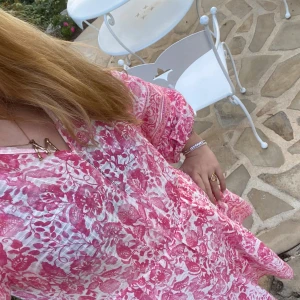 Rosa blommig klänning - Säljer en söt rosa blommig klänning med trekvartsärm🌸Klänningen har en luftig passform och rosa blommönster. 