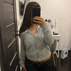 Grå hoodie från Calvin Klein Jeans - Säljer en stilren grå hoodie från Calvin Klein Jeans. Den har en dragkedja framtill och en justerbar huva med snören. Jättefin passform på.
