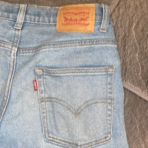 Levi’s - Säljer ett par ljusblå jeans från Levi's med klassisk femficksdesign och knappgylf. Jeansen har en straight passform och är perfekta för en avslappnad stil. Levi's logotyp finns på bakfickan. Pris ej hugget i sten👀