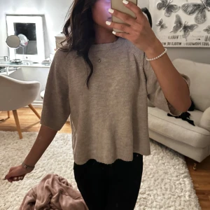 Beige stickad tröja - Säljer en stilren beige stickad tröja med trekvartsärm. Perfekt för en avslappnad look. Tröjan har en mjuk och bekväm passform.