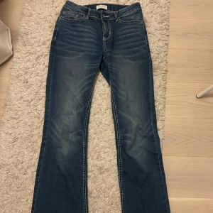 Blå bootcut jeans - Snygga blå bootcut jeans med klassisk femficksdesign och ljusa tvättade detaljer. De har en normal passform och är tillverkade i ett slitstarkt denimtyg.